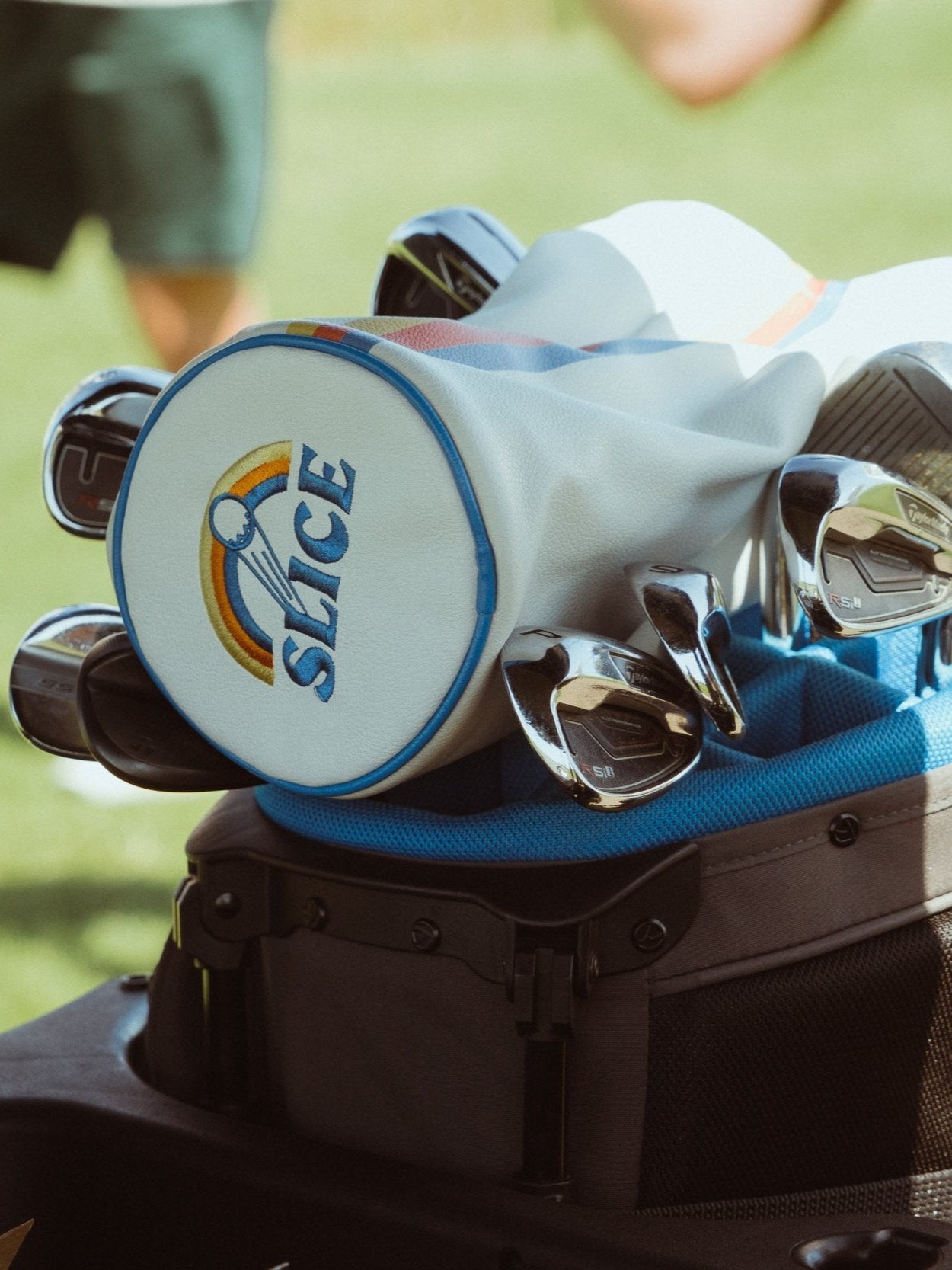 Golf Driver Head Cover in cream with blue, orange and yellow details on top of golf bag.
