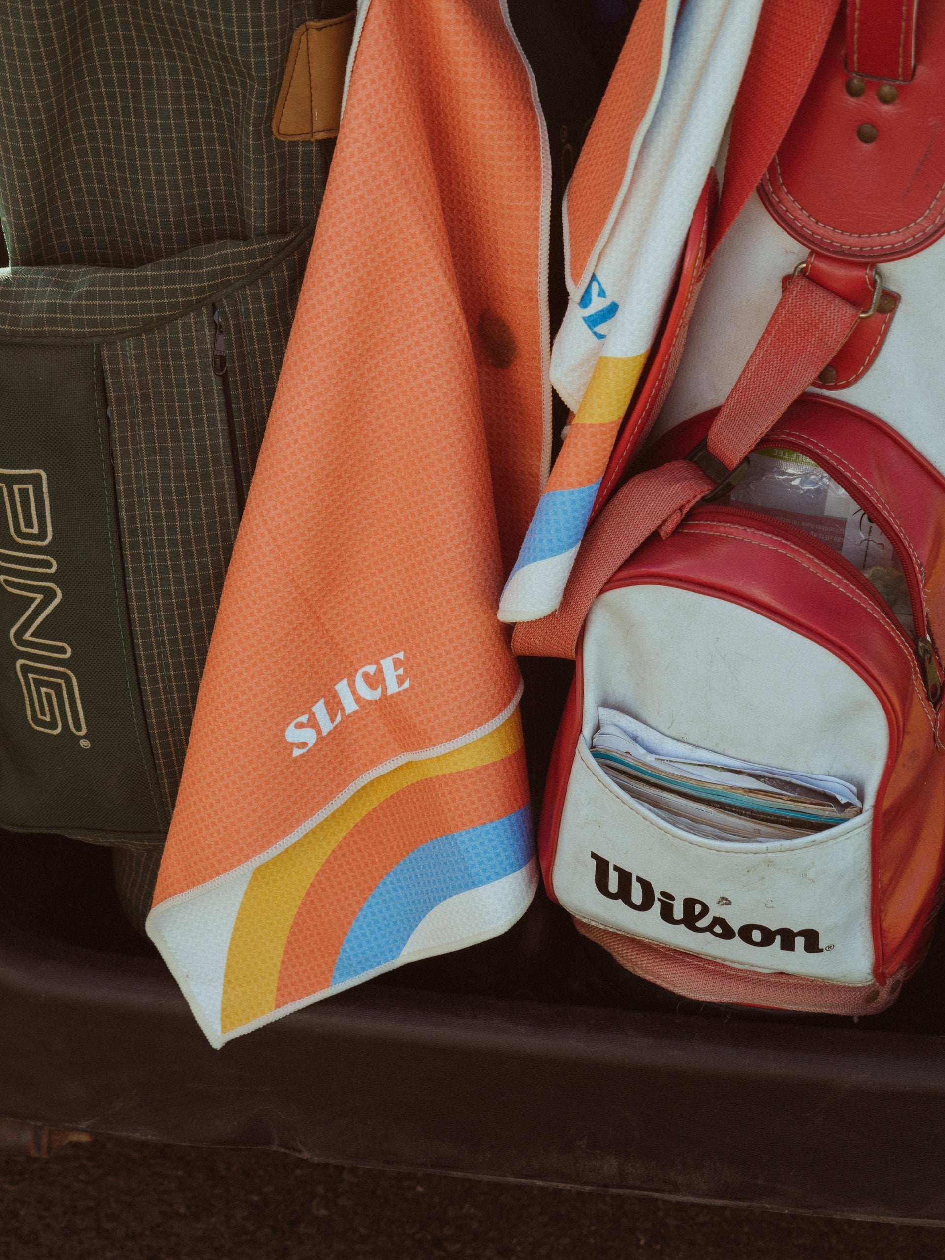 Golf towel in off-white, blue, orange and yellow on a golf bag