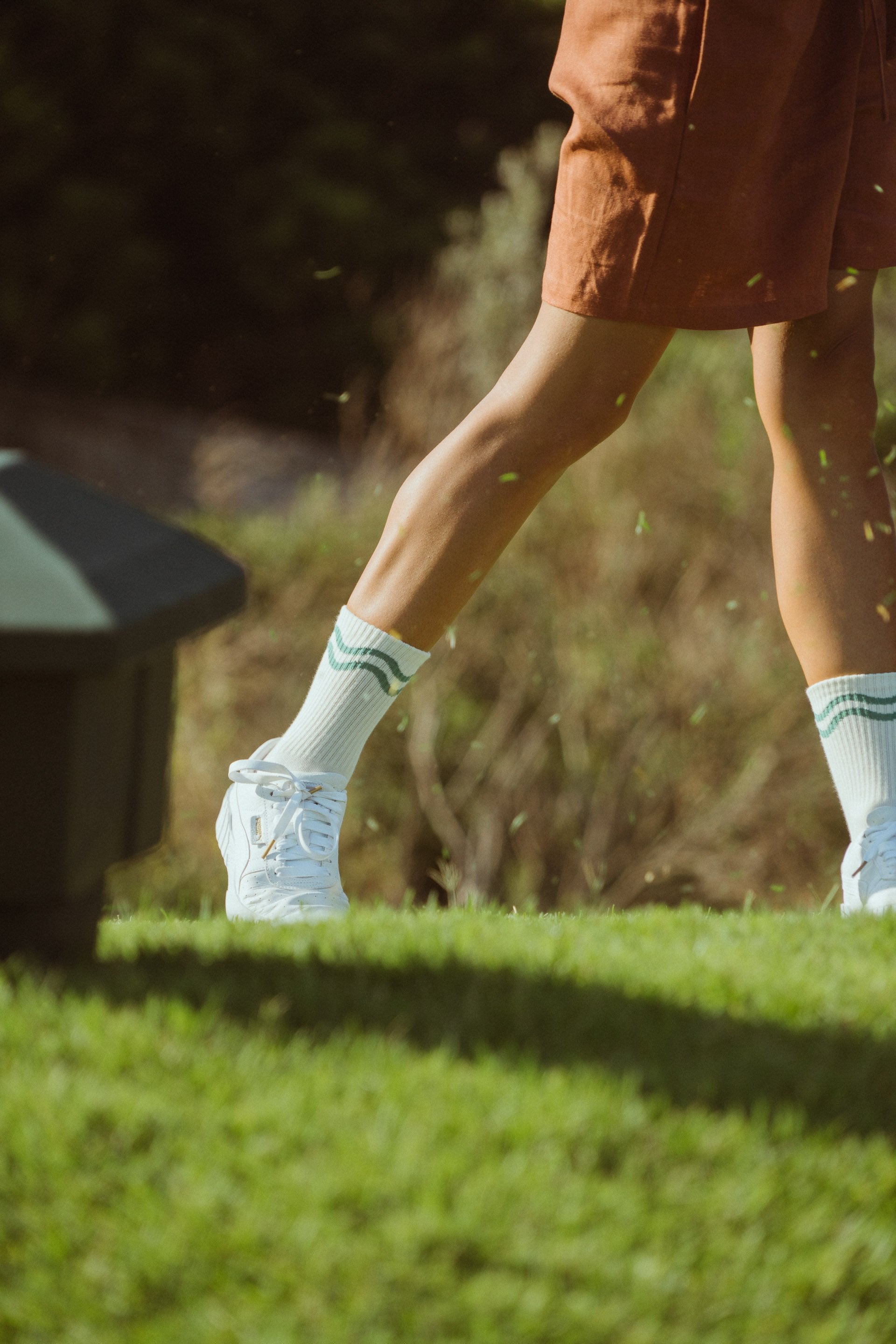Golf sports socks in off-white and green with green wavy lines show on model playing golf