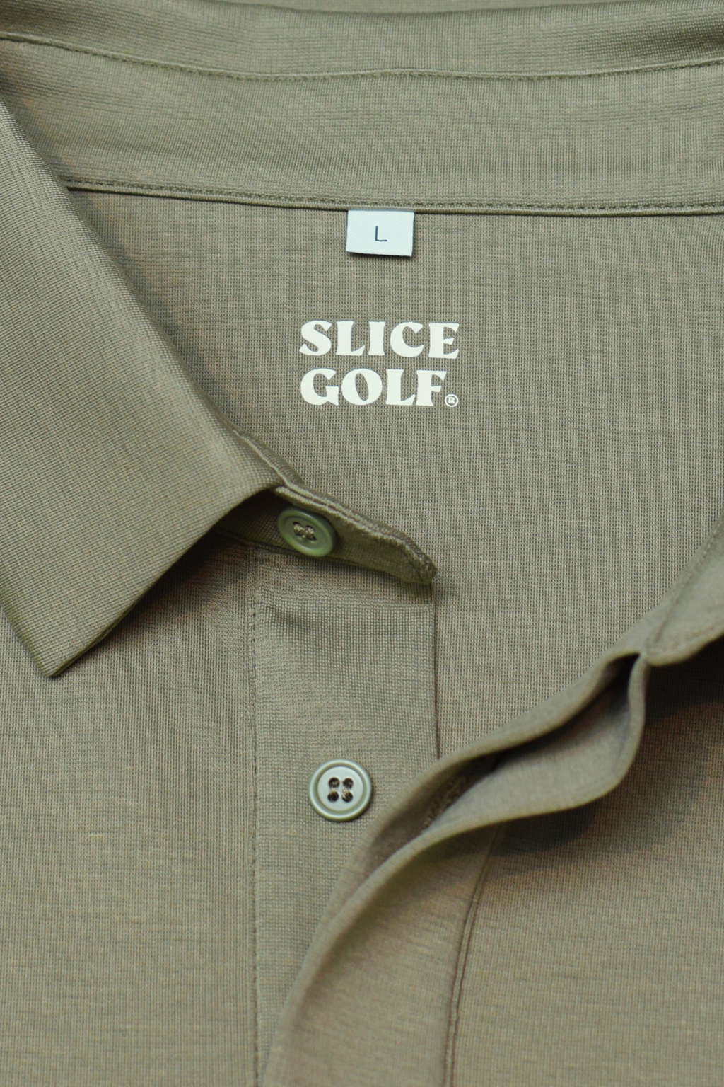 Green polo shirt with 'Slice Golf' label on a textured surface