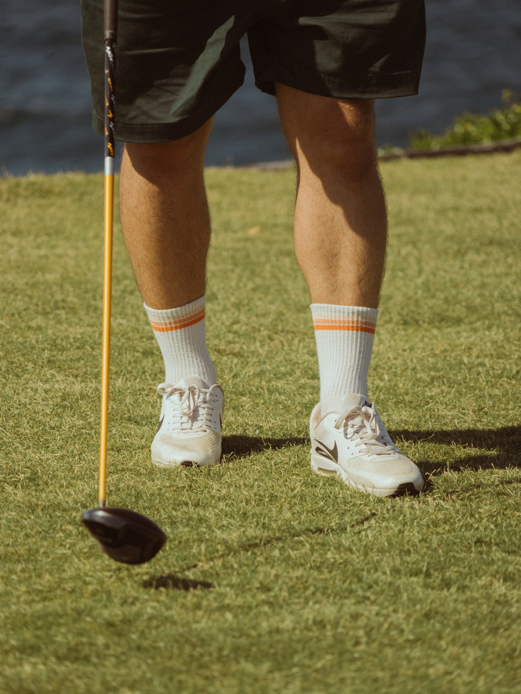 Golf sports socks in white with orange stripes on model.