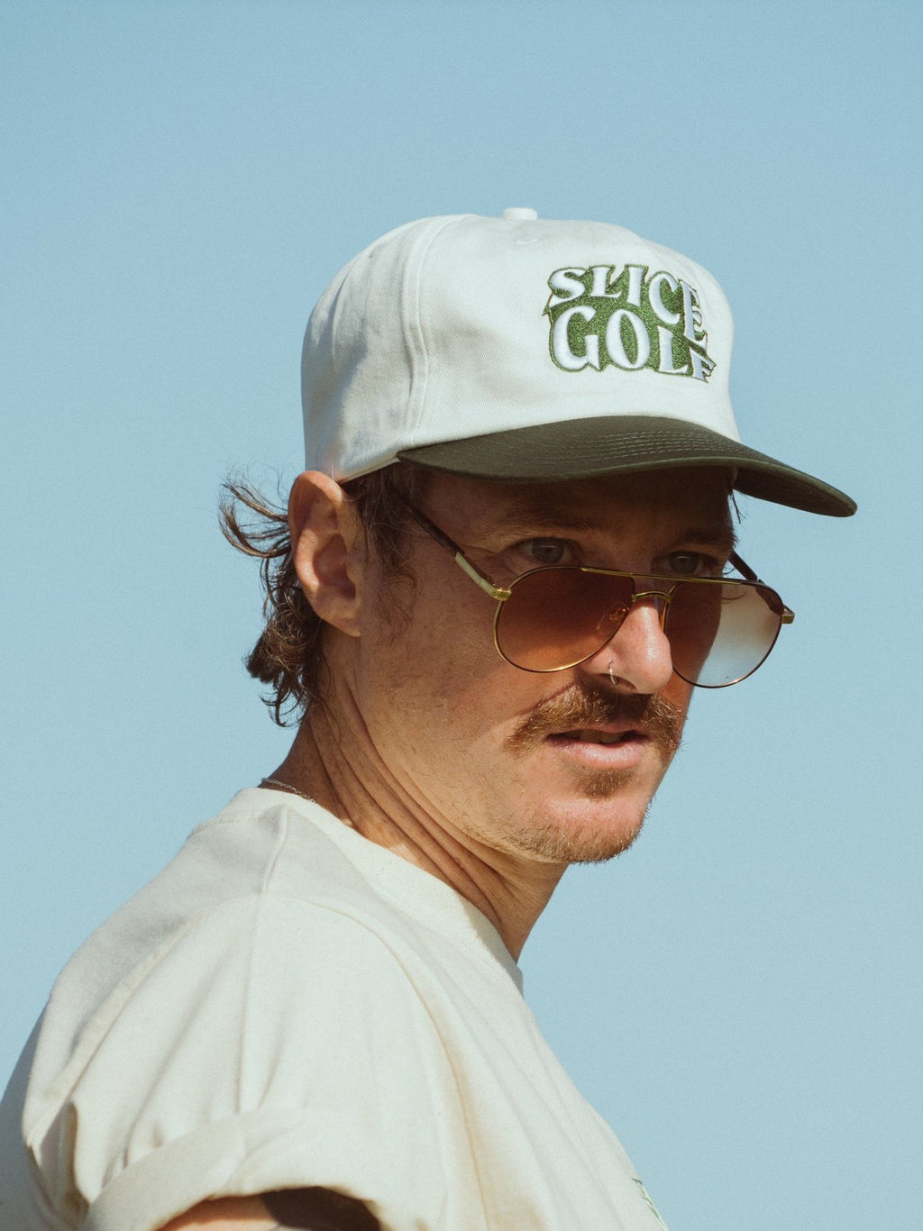 Golf cap in white and green on model wearing sunglasses