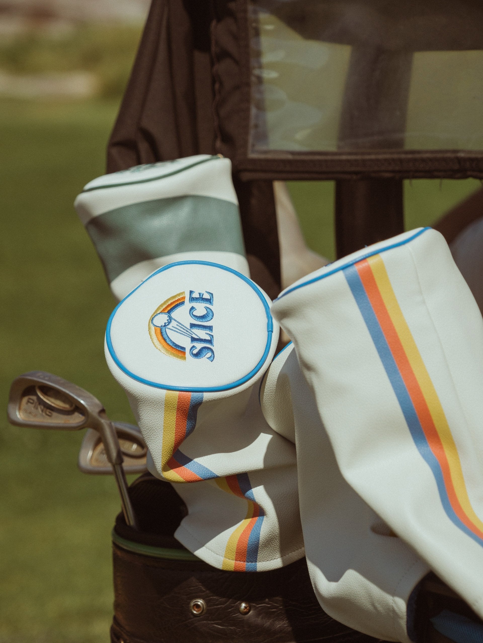 Golf Driver Head Cover in cream with blue, orange and yellow details on top of golf bag.