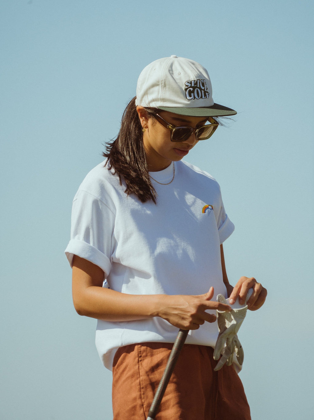 Golf T-shirt in white with Slice Golf Rainbow logo on left chest on model.